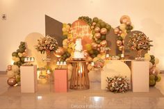 a table topped with lots of balloons and flowers next to a wall covered in balloons