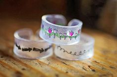 three bracelets with flowers on them sitting on top of a wooden table next to each other