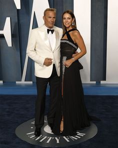 a man in a tuxedo standing next to a woman on a blue carpet