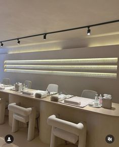 a long table with white chairs in front of it and some lights on the wall