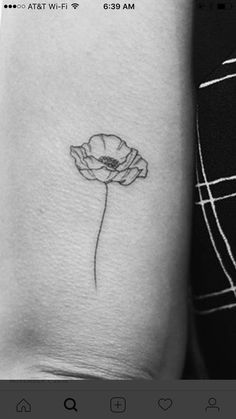 a black and white photo of a flower tattoo on the left side of the arm