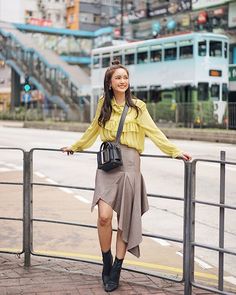 a woman standing next to a metal fence with her hands on the top of her hips