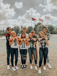 a group of young people standing next to each other on top of a grass covered field