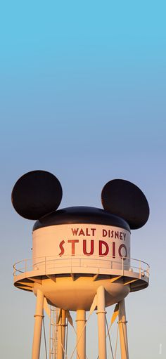 the top of a water tower with mickey mouse ears on it's head and words that read walt studio