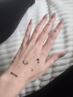 a woman's hand with small tattoos on it and an arrow tattoo on the middle finger