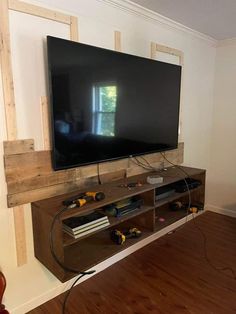 a flat screen tv mounted to the side of a wooden entertainment center in a living room