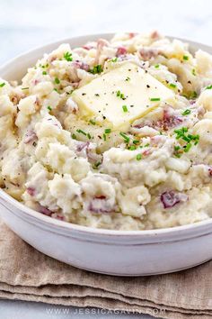 mashed potatoes with butter and parsley in a white bowl on top of a napkin