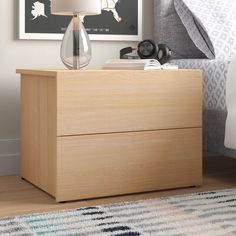 a nightstand with a lamp on it next to a bed