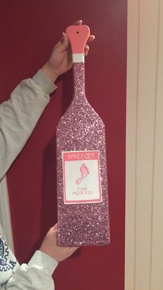 a person holding up a pink bottle shaped like a fish on the side of a red wall