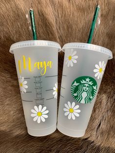 two starbucks cups sitting next to each other on top of a fur covered surface,