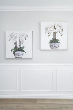 two white vases with flowers in them are on the wall next to each other