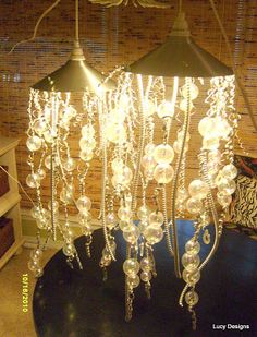 a chandelier made out of glass beads on a table with a lamp in the background