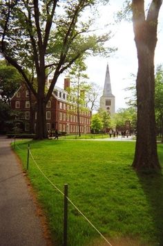 a grassy field in front of a building with a steeple on the other side