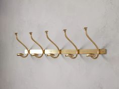 four brass hooks hang on the wall