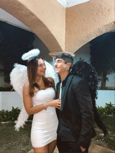 a man and woman dressed up as angels in front of a building with an angel wing