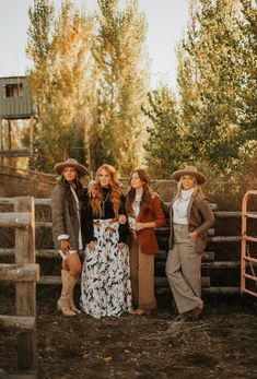 three women standing next to each other in front of a fence