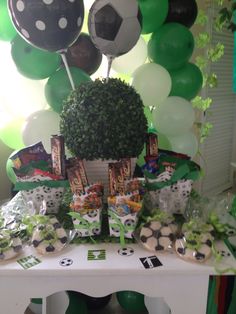 a table topped with lots of desserts and balloons in the shape of soccer balls