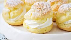 small pastries on a white plate with powdered sugar and icing around them