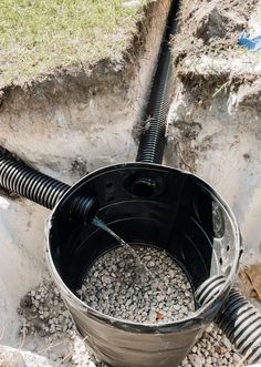 a bucket filled with gravel next to a pipe