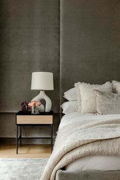 a bedroom with a bed, night stand and lamp on the side table in front of it