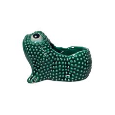 a green ceramic animal sitting on top of a white surface