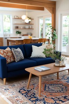 a living room with blue couches and rugs in front of large windows that look out onto the backyard