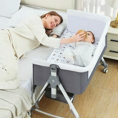 a woman laying on top of a bed next to a baby in a crib