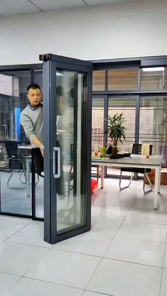 an office cubicle with a man sitting on the glass door and working on his laptop