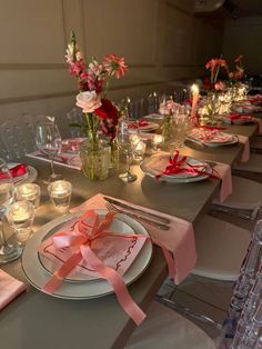 the table is set with pink and white plates, silverware, candles and flowers