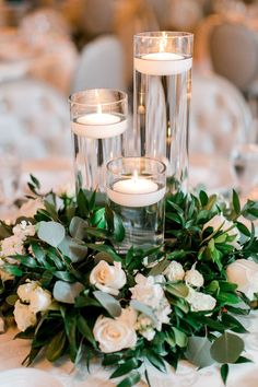 the centerpiece is surrounded by candles and greenery, with white roses on it