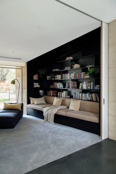 a living room with couches and bookshelves next to a sliding glass door