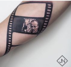 a man's arm with a film strip tattoo design on the left side of his arm