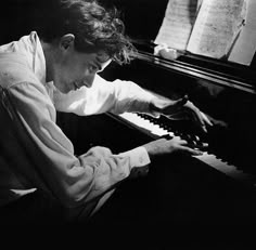 a man sitting at a piano with his hands on the keys and looking down while playing it