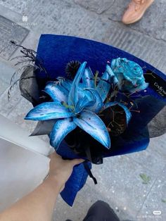 a person holding a blue hat with flowers in it