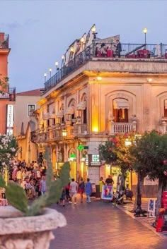 people are walking down the street in front of an old building with balconies