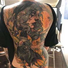 the back of a man's tattoo with cats and pumpkins on his chest