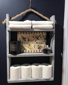 a shelf with two rolls of toilet paper on it and some other items hanging from the wall