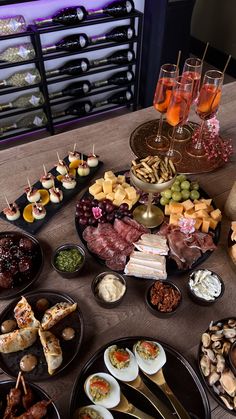 a table topped with lots of different types of food and wine glasses on top of it