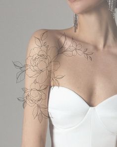 a woman with tattoos on her arm wearing a strapless white dress and silver earrings