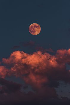 the full moon is seen through some clouds