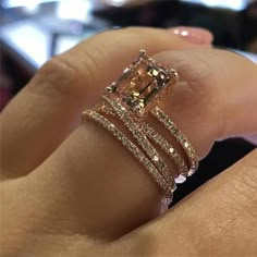 a woman's hand holding an engagement ring with two bands and a fancy yellow diamond