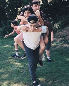 a group of young people standing on top of each other in front of some trees