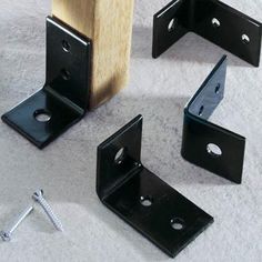 three black brackets and two screws laying on the ground next to each other,