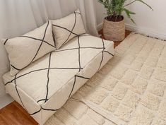 a white couch sitting on top of a wooden floor next to a potted plant