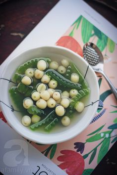 a white bowl filled with green vegetables on top of a table next to a spoon