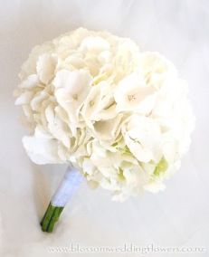 a bouquet of white flowers sitting on top of a white cloth covered tablecloth,