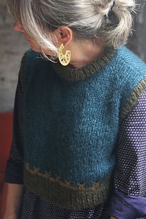 an older woman wearing a sweater with a gold earring on her left ear is looking down at the ground