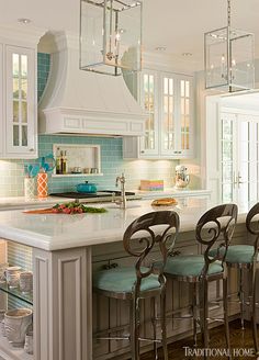 a kitchen with white cabinets and blue backsplashes, an island with four stools