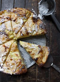 a pie with powdered sugar on top sitting on a wooden table