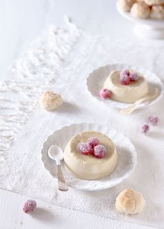 two small white plates with desserts on them sitting on a lace tablecloth next to other dishes